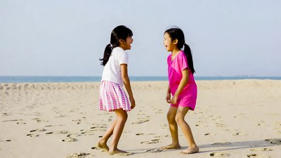 Two Asian girls laughing on beach