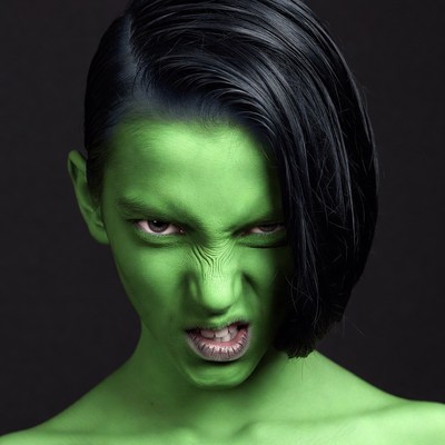 Green-faced woman making angry grimace