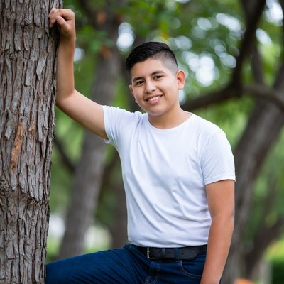 Latino boy leaning against tree