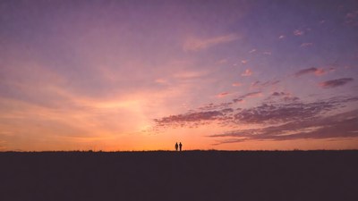 Silhouettes of couple on hill at sunset