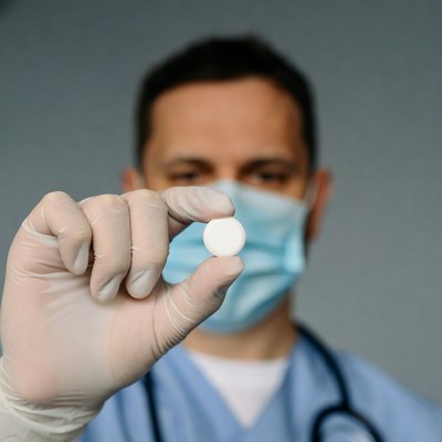 Doctor holding pill in gloved hand
