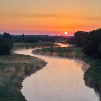 Sunset over winding river with mist