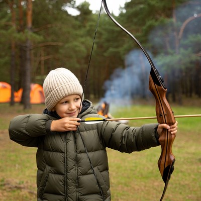 Boy shooting bow and arrow in forest