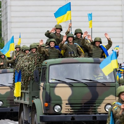 Ukrainian soldiers waving flags on military truck