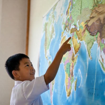 Asian boy pointing at world map