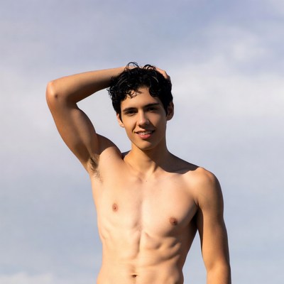 Shirtless young man flexing arm outdoors
