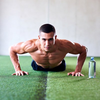 Muscular man doing pushups on turf