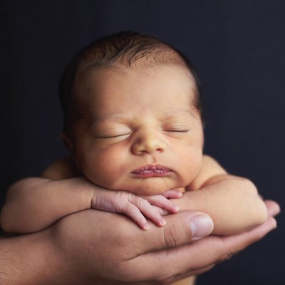 Man's hands cradling newborn baby