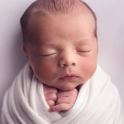 Newborn baby sleeping in white swaddle