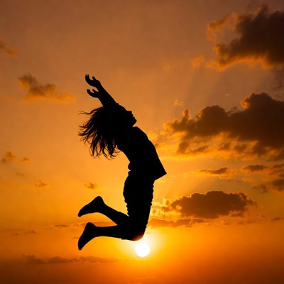 Silhouette woman jumping at sunset