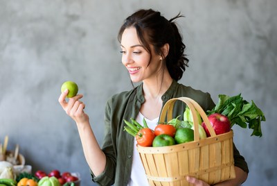 Woman holding basket of fresh vegetables