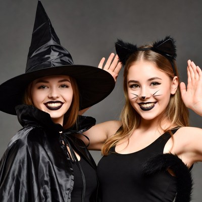 Two girls in witch and cat Halloween costumes