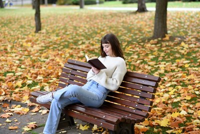 Woman reading book on park bench