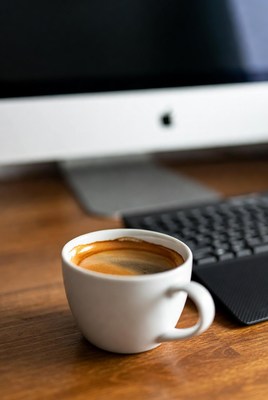 Coffee cup beside computer keyboard