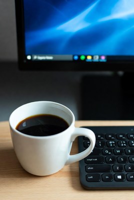Coffee cup on desk by computer