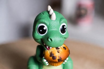 Cute green dinosaur eating muffin