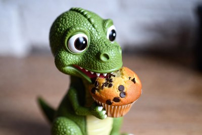 Cute green dinosaur eating muffin