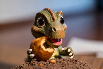 Cute baby dinosaur eating donut
