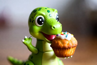 Green dinosaur toy eating cupcake