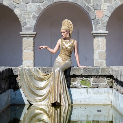 Woman in gold gown by stone arches