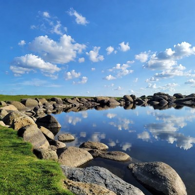 Rock-Lined Pond Reflecting Blue Sky