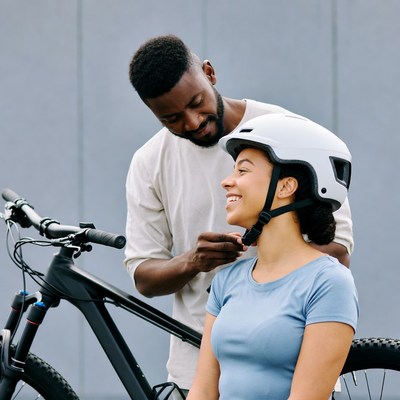 Man adjusting woman's bike helmet