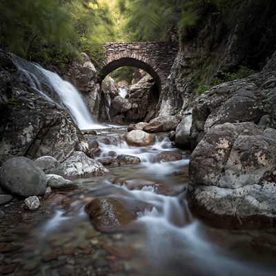 Stone Arch Bridge over Waterfall Stream