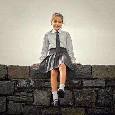 Girl in school uniform on stone wall