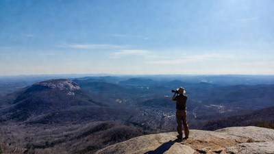 Woman photographing mountains from cliff