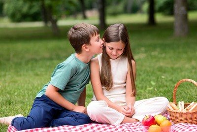 Boy whispering to girl at picnic