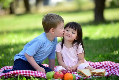 Boy kissing girl on picnic blanket