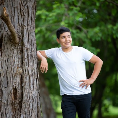 Latino teen leaning against tree