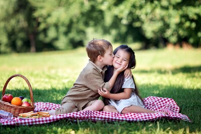 Boy kissing girl on picnic blanket