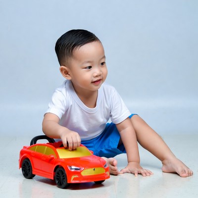 Asian toddler playing with red toy car