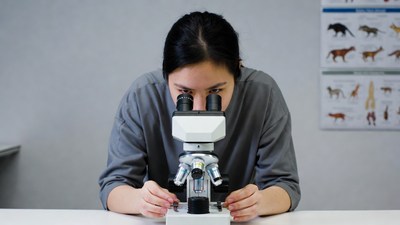 Asian woman using microscope in lab