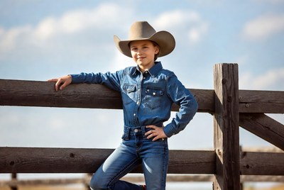 Girl in cowboy hat leaning on fence