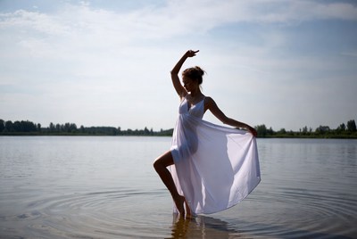 Woman dancing in white dress in water