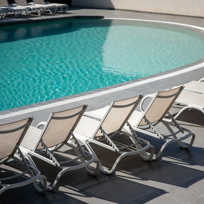 Empty lounge chairs by swimming pool