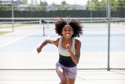 African-American girl running on tennis court