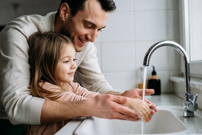 Father helping daughter wash hands