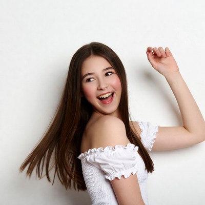 Smiling girl dancing in white off-shoulder top