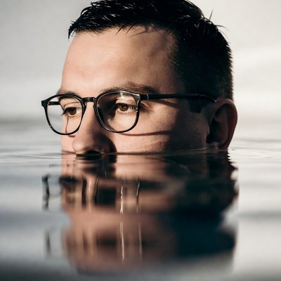 Man with glasses in water reflection