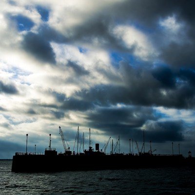 Ship Silhouette with Cranes Against Stormy Sky