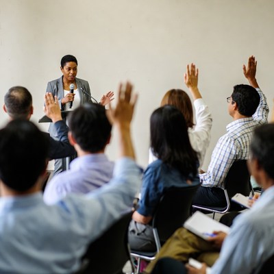 African-American woman leading classroom with raised hands