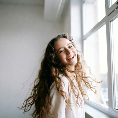 Smiling woman with wavy hair by window