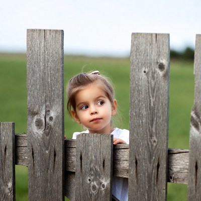 Curious girl peeking over wooden fence