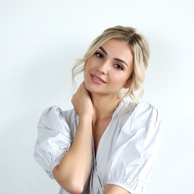 Blonde woman touching neck in blouse