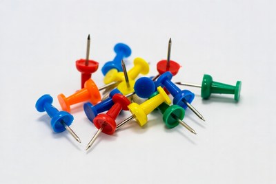 Colorful push pins on white background
