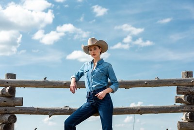 Woman in cowboy hat leaning on fence