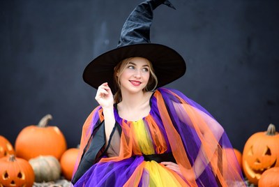 Woman in colorful witch costume with pumpkins